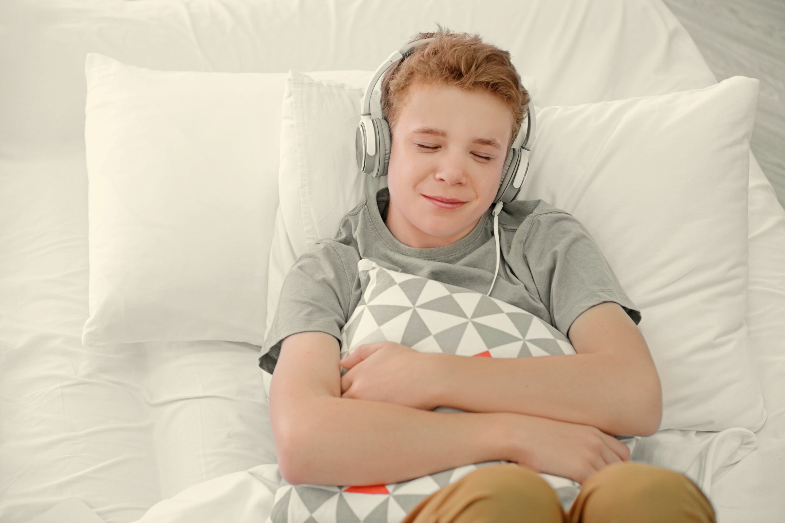 boy listening music headphones bed scaled