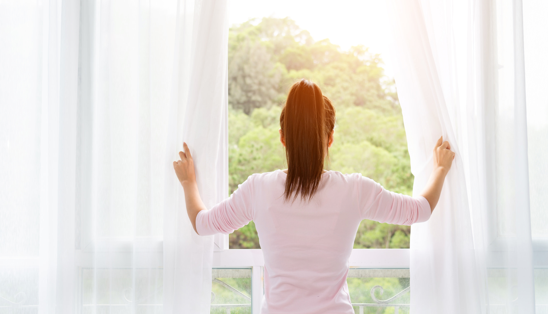 prostorna zračna bela spalnica ženska gleda skozi okno narava
